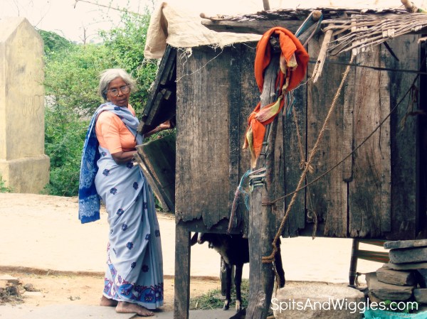 An elderly woman in a traditional sari, closing up shop